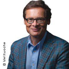 Ein Mann mit Brille und kariertem Sakko l&auml;chelt freundlich in die Kamera. Der Hintergrund ist wei&szlig;., &copy; links im Bild