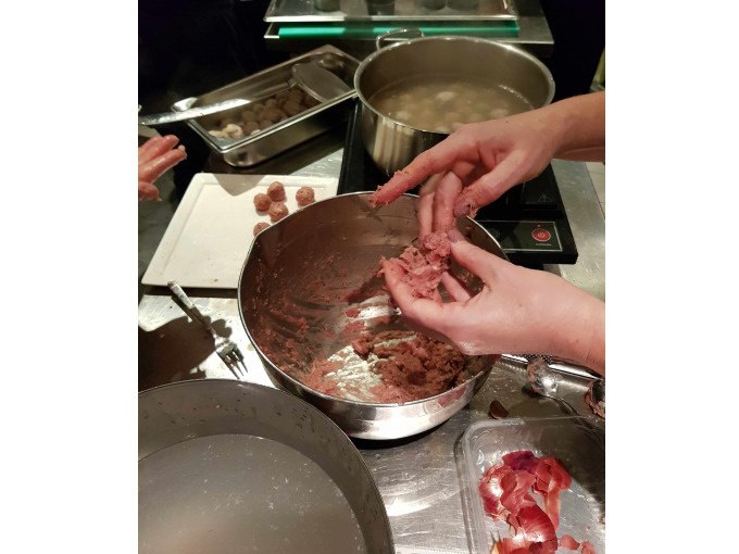 Eine Person formt Fleischbällchen aus Hackfleisch in einer Schüssel. Im Hintergrund sind Töpfe und Tabletts mit weiteren Zutaten zu sehen., © Kultweine-Kochwelten-Kunstücke - Kochschule Sonja Lenz Eine Person formt Fleischbällchen aus Hackfleisch in einer Schüssel. Im Hintergrund sind Töpfe und Tabletts mit weiteren Zutaten zu sehen., © Kultweine-Kochwelten-Kunstücke - Kochschule Sonja Lenz
