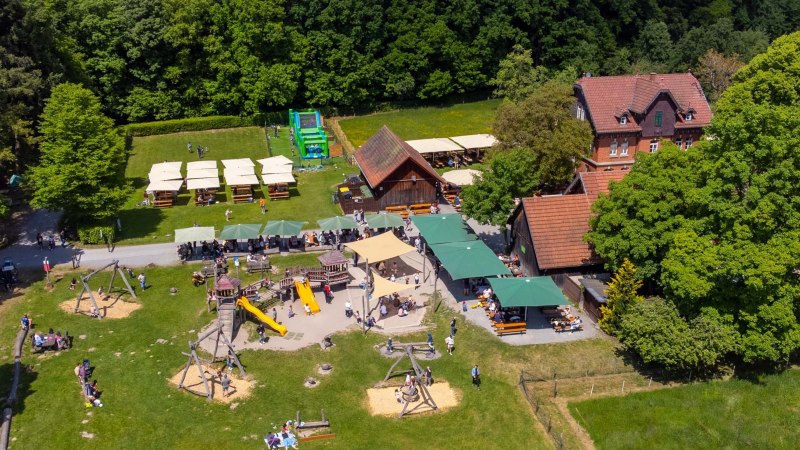 Luftaufnahme des Katzenbacher Hofs mit Spielplatz, Biergarten und grüner Umgebung. Menschen genießen das sonnige Wetter im Freien., © Katzenbacher Hof Luftaufnahme des Katzenbacher Hofs mit Spielplatz, Biergarten und grüner Umgebung. Menschen genießen das sonnige Wetter im Freien., © Katzenbacher Hof