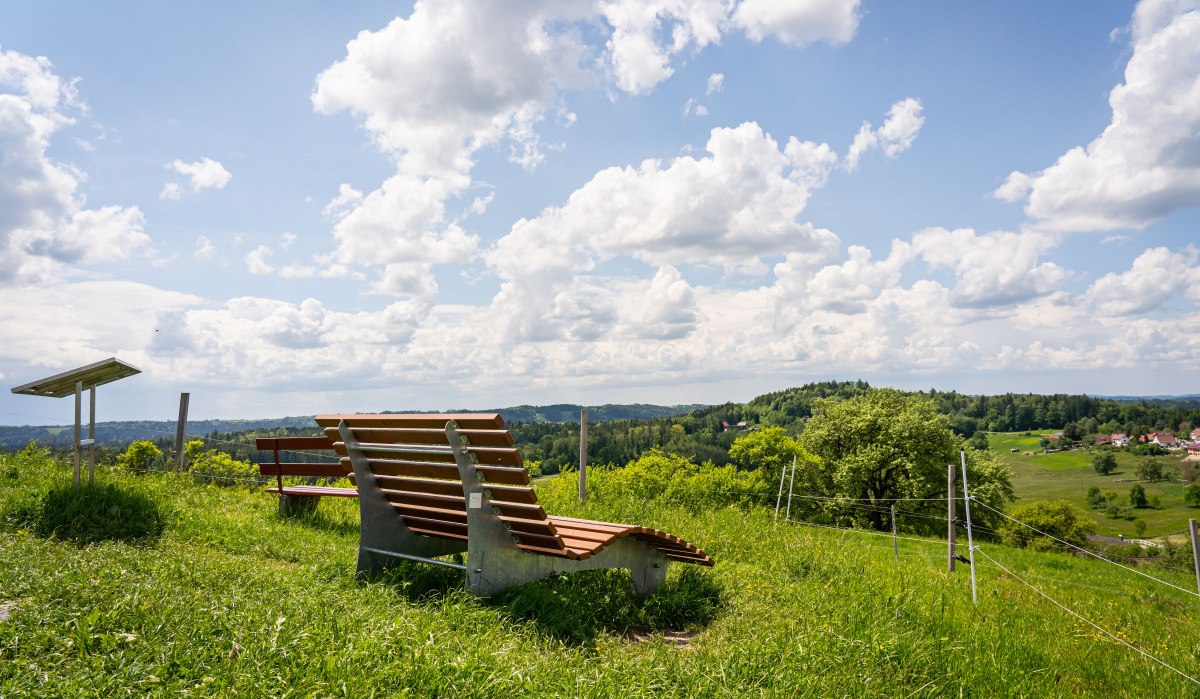 Ruheliege auf einer grünen Wiese am Aussichtspunkt "Hohe Tanne" mit Blick auf eine hügelige Landschaft und einen bewölkten Himmel., © agentur arcos/Niki Eilers