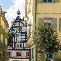 Blick auf ein historische Fachwerkhaus in Bad &Uuml;berkingen, eingerahmt von bunten Geb&auml;uden, dem Rathaus und einem Baum im Vordergrund., &copy; SMG, Sarah Schmid