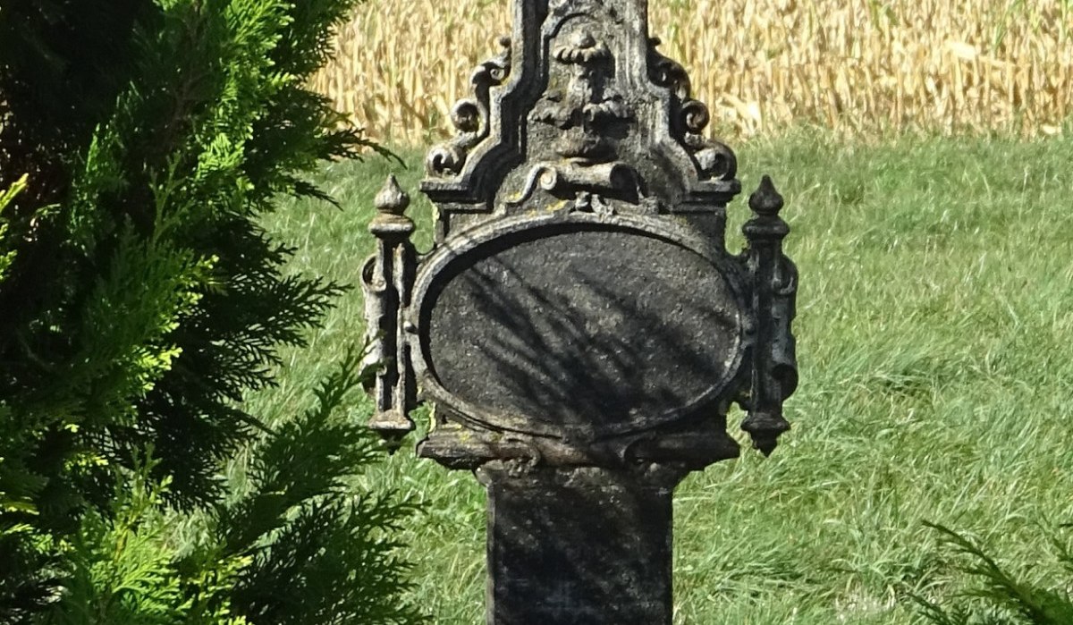 Ein verziertes Steinkreuz mit Jesusfigur steht in einer grünen Landschaft, umgeben von Büschen und Feldern., © Foto: Cornelia Steinbach Ein verziertes Steinkreuz mit Jesusfigur steht in einer grünen Landschaft, umgeben von Büschen und Feldern., © Foto: Cornelia Steinbach