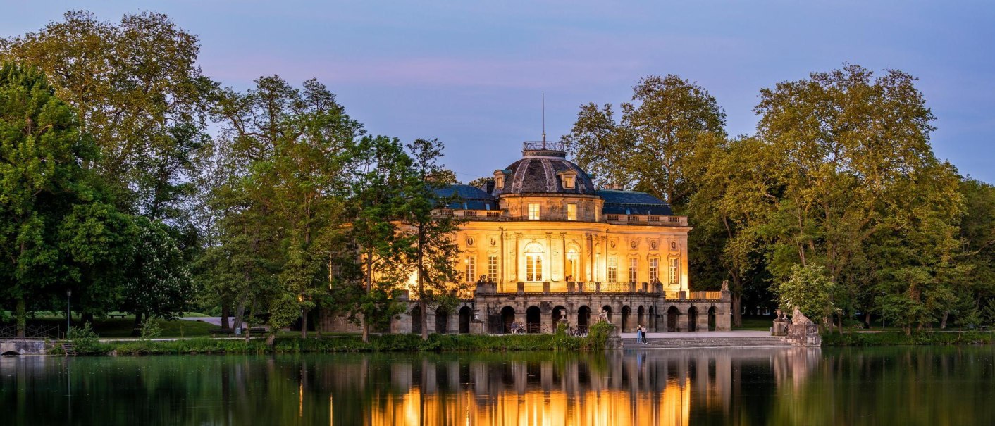 Das beleuchtete Schloss Monrepos spiegelt sich nachts im ruhigen See, umgeben von &uuml;ppigen B&auml;umen., &copy; &copy; Stuttgart-Marketing GmbH, Werner Dieterich