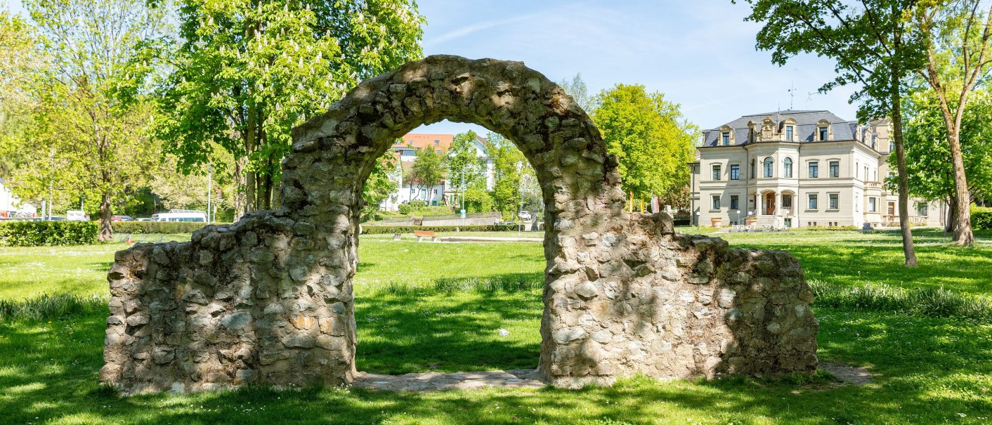 heller Ruinenbogen auf grüner Wiese, rechts im Hintergrund das helle Steingebäude des Neuen Schlosses, © Stadt Gaildorf