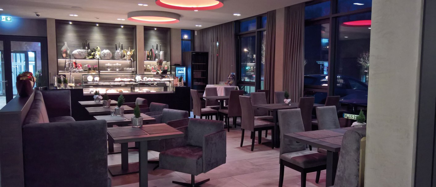 Ein stilvoll eingerichtetes Restaurant mit modernen Möbeln, dekorativer Beleuchtung und einer Vitrine mit Desserts. Die Atmosphäre wirkt einladend und elegant., © Hotel Eislinger Tor