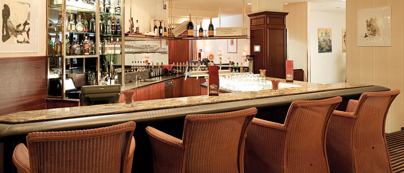 Elegante Hotelbar mit Rattanstühlen, Marmortheke und beleuchtetem Regal voller Spirituosen. Dezente Beleuchtung und stilvolle Dekoration., © Seminaris Hotel Bad Boll Elegante Hotelbar mit Rattanstühlen, Marmortheke und beleuchtetem Regal voller Spirituosen. Dezente Beleuchtung und stilvolle Dekoration., © Seminaris Hotel Bad Boll