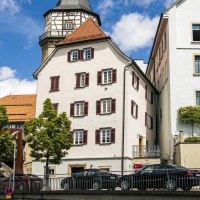 Bandhaus und Helferhaus in Backnang bei sonnigem Wetter mit wei&szlig;er Fassade, Fachwerkturm und B&auml;umen davor., &copy; SMG, Sarah Schmid