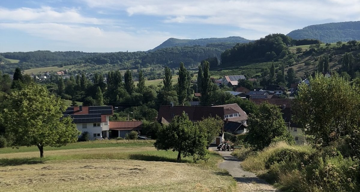 Blick auf ein Dorf in einer hügeligen Landschaft mit grünen Wiesen und Bäumen unter einem blauen Himmel mit weißen Wolken., © Touristik und Marketing GmbH Blick auf ein Dorf in einer hügeligen Landschaft mit grünen Wiesen und Bäumen unter einem blauen Himmel mit weißen Wolken., © Touristik und Marketing GmbH