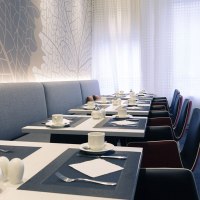 Ein modernes Restaurant mit gedeckten Tischen, weißen Tassen und Tellern. Helle Wände und Vorhänge schaffen eine einladende Atmosphäre., © Mercure Hotel Stuttgart City Center