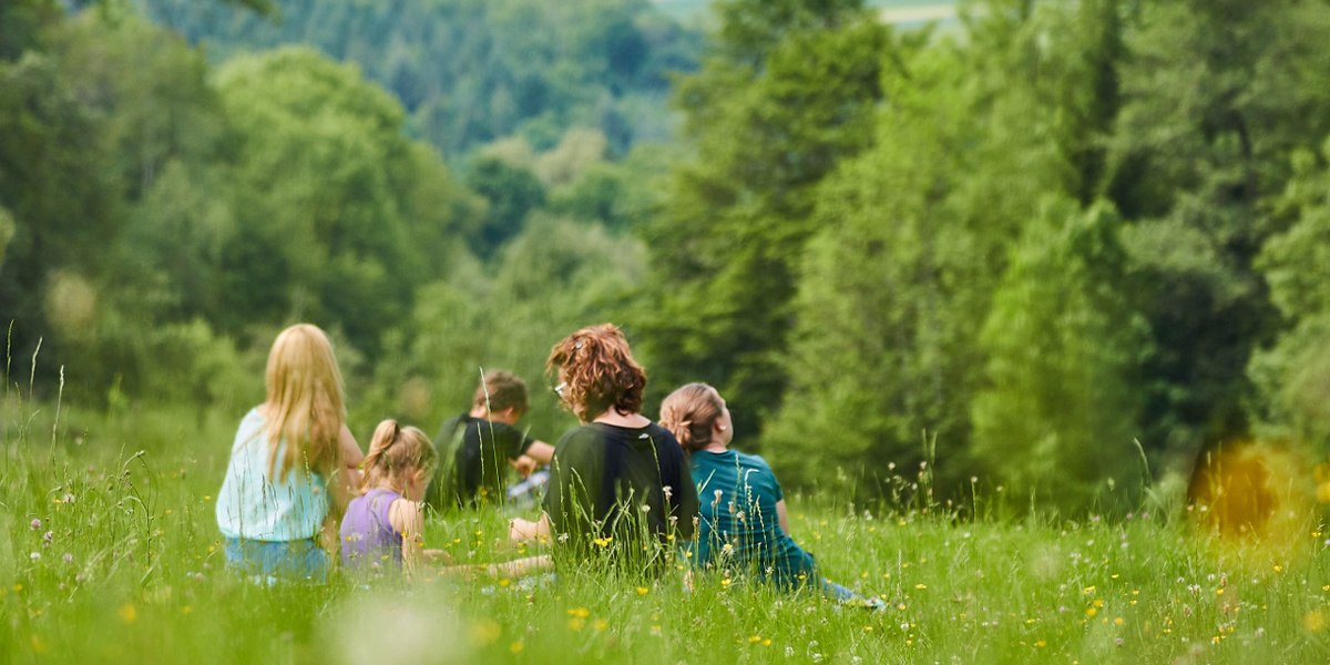 Menschen sitzen auf einer blühenden Wiese, umgeben von grünen Bäumen. Sie genießen die Natur in entspannter Atmosphäre., © Stadt Waldenbuch