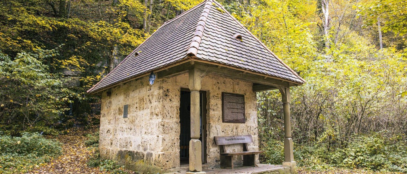Eine kleine Steinkapelle mit Ziegeldach im Wald, umgeben von Herbstlaub. Vor der Kapelle steht eine Bank mit der Aufschrift 'Kapelle Güterstein'., © Stuttgart-Marketing GmbH, Sarah Schmid Eine kleine Steinkapelle mit Ziegeldach im Wald, umgeben von Herbstlaub. Vor der Kapelle steht eine Bank mit der Aufschrift 'Kapelle Güterstein'., © Stuttgart-Marketing GmbH, Sarah Schmid