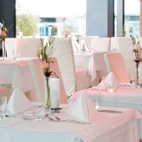 Elegantes Restaurant mit weißen Tischdecken, stilvoll gedeckten Tischen und Blumenarrangements. Helle, moderne Einrichtung mit großen Fenstern., © AMICI