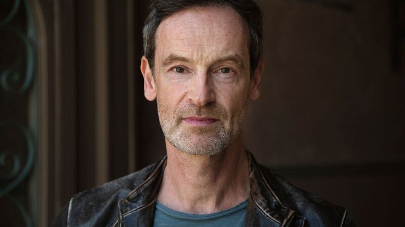 Ein Mann mit Lederjacke und grauem T-Shirt blickt ernst in die Kamera. Der Hintergrund ist unscharf., © Stadthalle Leonberg