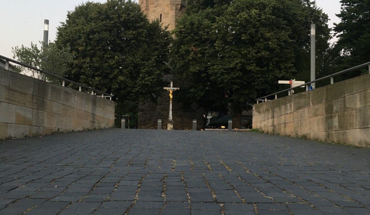 Pflasterweg mit roter Blumenmarkierung, führt zu einem historischen Turm, umgeben von Bäumen., © Touristik und Marketing GmbH Pflasterweg mit roter Blumenmarkierung, führt zu einem historischen Turm, umgeben von Bäumen., © Touristik und Marketing GmbH