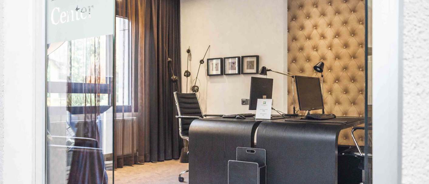 Ein elegantes Büro mit Schreibtischen, Stühlen und Computern, durch eine Glastür mit der Aufschrift 'Business Center' sichtbar., © Chandler Photography Ein elegantes Büro mit Schreibtischen, Stühlen und Computern, durch eine Glastür mit der Aufschrift 'Business Center' sichtbar., © Chandler Photography