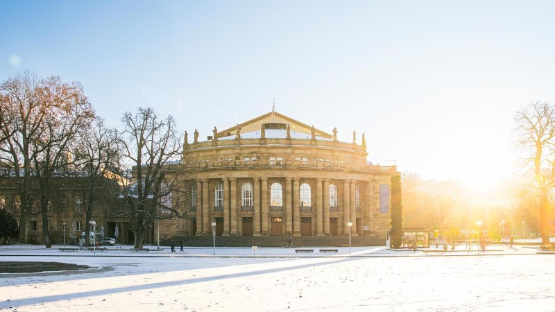 Die Stuttgarter Staatsoper im Winter, umgeben von schneebedecktem Boden und kahlen B&auml;umen. Die Sonne geht im Hintergrund auf und taucht die Szene in warmes Licht., &copy; Stuttgart-Marketing GmbH, Sarah Schmid