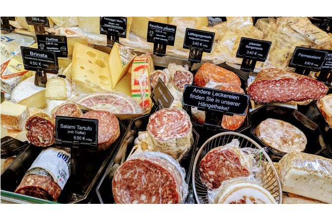 Verschiedene Käsesorten und Wurstwaren in einer Markthalle. Preisschilder zeigen die Auswahl an Delikatessen., © WTM GmbH Waiblingen