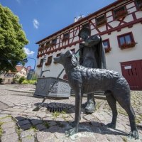 Bronzestatue eines Hirten mit Hund vor einem Fachwerkhaus in Schafhausen. Der gepflasterte Platz und blauer Himmel erg&auml;nzen die Szene., &copy; Stadtverwaltung Weil der Stadt