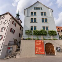 Das Bandhaus Theater in Backnang mit benachbarten historischen Gebäuden. Ein Plakat fordert zur Einhaltung von Abstand auf. Der Himmel ist bewölkt., © Stuttgart Marketing GmbH, Fotografin Martina Denker