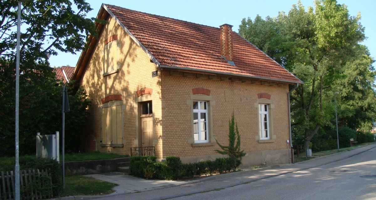 Ein kleines Backsteinhaus mit rotem Ziegeldach und Schornstein, umgeben von Bäumen und einer Straße., © Land der 1000 Hügel - Kraichgau-Stromberg Ein kleines Backsteinhaus mit rotem Ziegeldach und Schornstein, umgeben von Bäumen und einer Straße., © Land der 1000 Hügel - Kraichgau-Stromberg