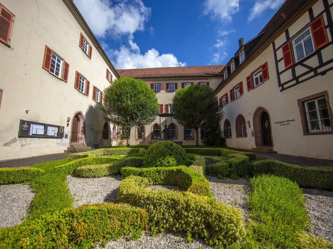 Historischer Innenhof mit gepflegtem Garten und B&auml;umen, umgeben von Geb&auml;uden mit roten Fensterl&auml;den und Fachwerkdetails., &copy; Stadtverwaltung Weil der Stadt
