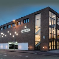 Modernes Hotelgebäude bei Nacht, beleuchtet mit großen Fenstern und Schildern. "Himmelreich Restaurant & Eventlocation" ist sichtbar., © Hotel Reich an der Rems