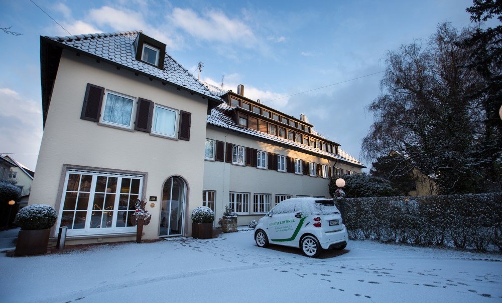 Ein Hotelgeb&auml;ude im Winter, bedeckt mit Schnee. Ein Auto mit der Aufschrift 'Hotel' steht davor. Der Himmel ist blau mit wenigen Wolken., &copy; Hotel B&uuml;rkle