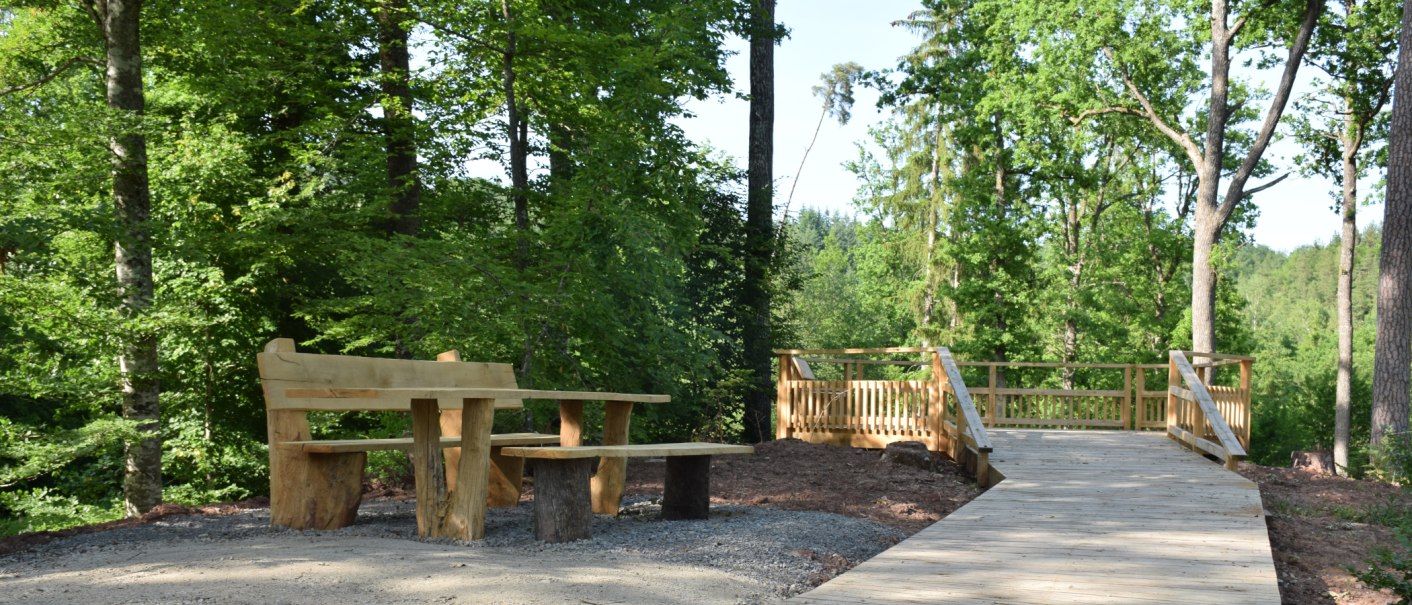 Eine rustikale Holzbank mit Tisch steht neben einem Holzsteg in einem grünen Wald. Die Umgebung ist ruhig und einladend., © Landratsamt Böblingen, Amt für Forsten Eine rustikale Holzbank mit Tisch steht neben einem Holzsteg in einem grünen Wald. Die Umgebung ist ruhig und einladend., © Landratsamt Böblingen, Amt für Forsten
