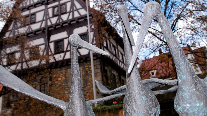 Störche aus Metall vor einem Fachwerkhaus im Städtischen Museum im Storchen Göppingen, umgeben von Bäumen und blauem Himmel., © Stuttgart-Marketing GmbH Störche aus Metall vor einem Fachwerkhaus im Städtischen Museum im Storchen Göppingen, umgeben von Bäumen und blauem Himmel., © Stuttgart-Marketing GmbH
