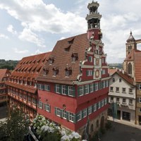 Das Alte Rathaus in Esslingen mit rotem Fachwerk und Turm, umgeben von historischen Gebäuden und blühenden Blumen im Vordergrund., © Esslinger Stadtmarketing & Tourismus GmbH
