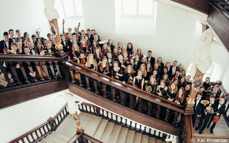 Das Landesjugendorchester Baden-Württemberg posiert auf einer Treppe in einem historischen Gebäude. Die Musiker halten ihre Instrumente., © Kultur- und Sportamt Stadt Bietigheim-Bissingen