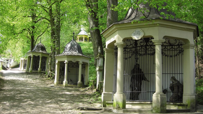 Ein Weg mit mehreren kleinen Kapellen in einem gr&uuml;nen Wald. Die Kapellen haben verzierte D&auml;cher und Gittert&uuml;ren. B&auml;ume spenden Schatten., &copy; LGS Schw&auml;bisch Gm&uuml;nd