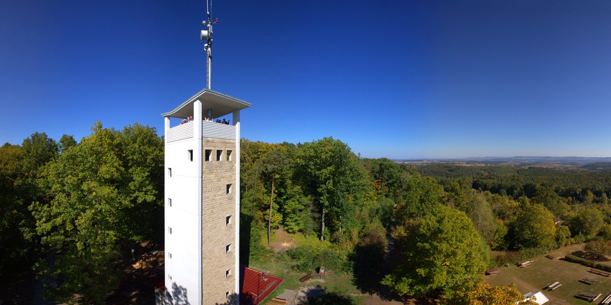 Der Uhlbergturm in Filderstadt erhebt sich über grüne Wälder, mit weitem Blick über die Landschaft unter klarem, blauem Himmel., © SMG Mende