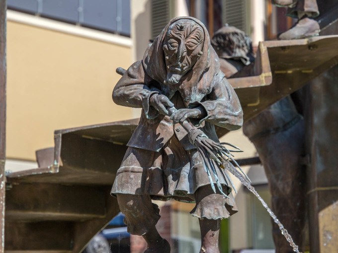 Bronzestatue einer alten Frau mit Regenschirm, aus dem Wasser flie&szlig;t. Die Figur ist Teil eines Brunnens in einer st&auml;dtischen Umgebung., &copy; Stadtverwaltung Weil der Stadt