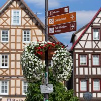 Fachwerkhäuser auf dem Marktplatz von Murrhardt mit einem Wegweiser und blühendem Blumenschmuck im Vordergrund., © Stuttgart-Marketing GmbH, Achim Mende Fachwerkhäuser auf dem Marktplatz von Murrhardt mit einem Wegweiser und blühendem Blumenschmuck im Vordergrund., © Stuttgart-Marketing GmbH, Achim Mende