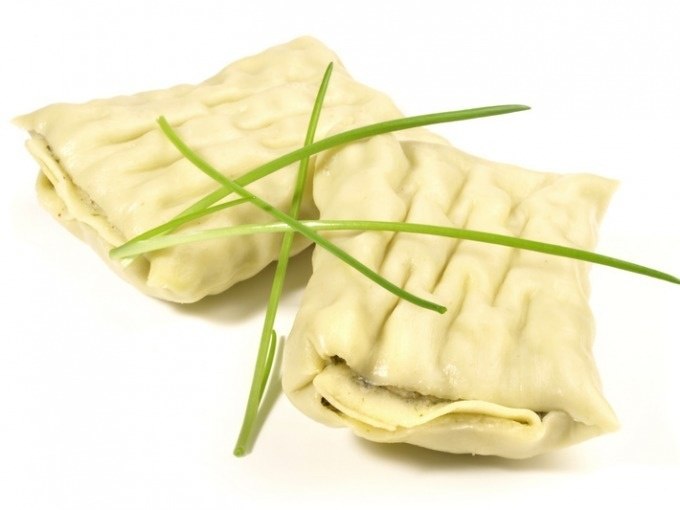 Zwei Maultaschen liegen auf einem weißen Hintergrund, garniert mit frischem Schnittlauch., © Cool-Tours StattReisen Zwei Maultaschen liegen auf einem weißen Hintergrund, garniert mit frischem Schnittlauch., © Cool-Tours StattReisen