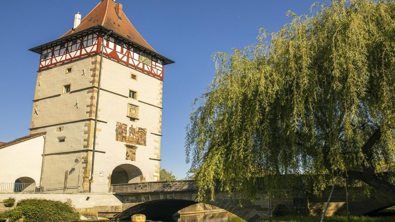 Das Beinsteiner Tor in Waiblingen mit Fachwerk und Brücke, umgeben von Bäumen, unter klarem Himmel., © SMG, Sarah Schmid