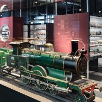 Eine grüne Modelllokomotive in einer Glasvitrine, umgeben von weiteren Modelleisenbahnen in einem Museumsausstellungsraum., © Märklineum Eine grüne Modelllokomotive in einer Glasvitrine, umgeben von weiteren Modelleisenbahnen in einem Museumsausstellungsraum., © Märklineum