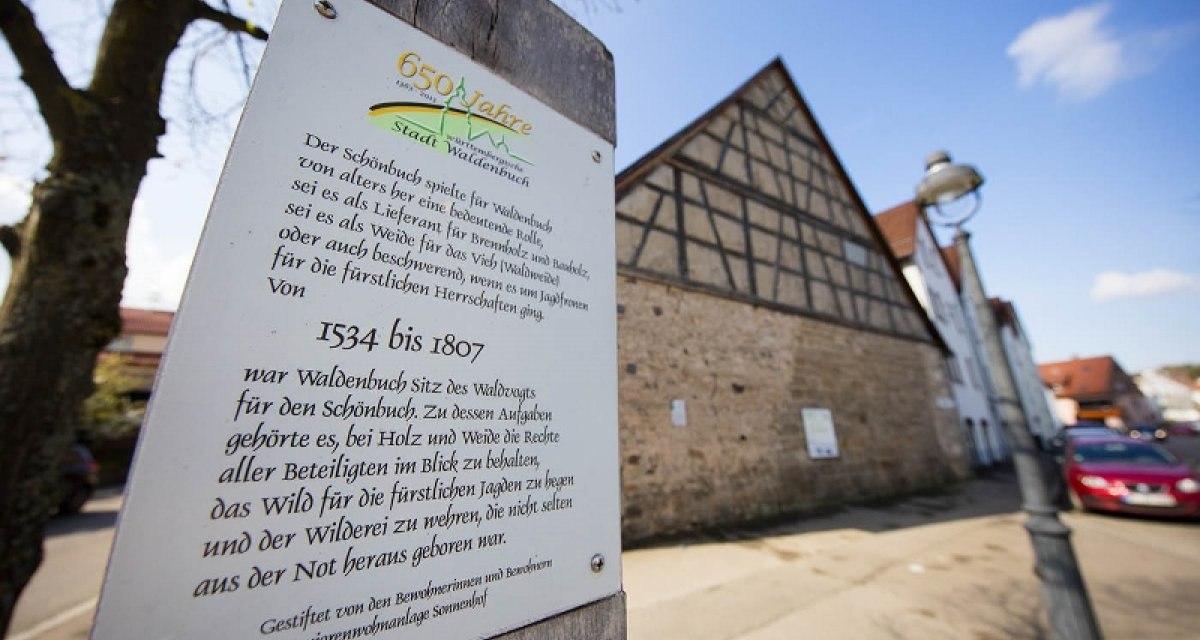 Gedenktafel in Waldenbuch erinnert an die historische Bedeutung des Sch&ouml;nbuchs. Im Hintergrund ein Fachwerkhaus und eine Stra&szlig;e mit Autos., &copy; Natur.Nah. Sch&ouml;nbuch & Heckeng&auml;u