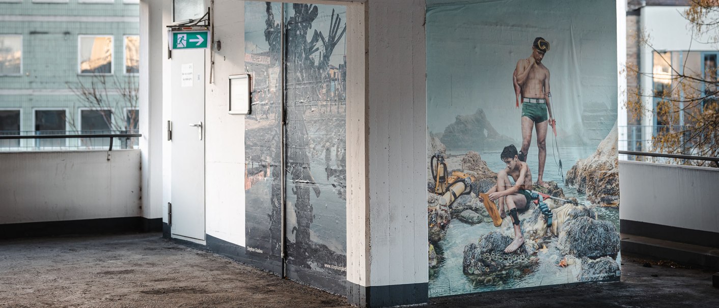 Wandbild in einem Parkhaus zeigt zwei Männer in Badebekleidung mit Tauchausrüstung. Im Hintergrund ein Gebäude mit Fenstern., © SMG Stuttgart Marketing GmbH -Sarah Schmid Wandbild in einem Parkhaus zeigt zwei Männer in Badebekleidung mit Tauchausrüstung. Im Hintergrund ein Gebäude mit Fenstern., © SMG Stuttgart Marketing GmbH -Sarah Schmid
