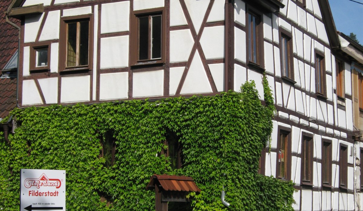 Ein Fachwerkhaus mit Efeu bewachsen. Straßenschilder weisen nach Filderstadt (4 km) und Nürtingen (15 km)., © Natur.Nah. Schönbuch & Heckengäu Ein Fachwerkhaus mit Efeu bewachsen. Straßenschilder weisen nach Filderstadt (4 km) und Nürtingen (15 km)., © Natur.Nah. Schönbuch & Heckengäu