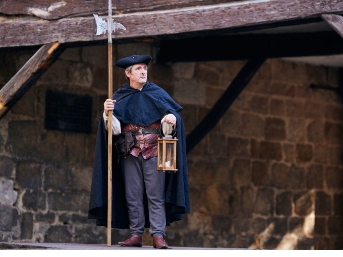 Ein Nachtwächter in historischer Kleidung steht mit Laterne und Hellebarde vor einer alten Steinmauer., © Esslinger Stadtmarketing & Tourismus GmbH Ein Nachtwächter in historischer Kleidung steht mit Laterne und Hellebarde vor einer alten Steinmauer., © Esslinger Stadtmarketing & Tourismus GmbH