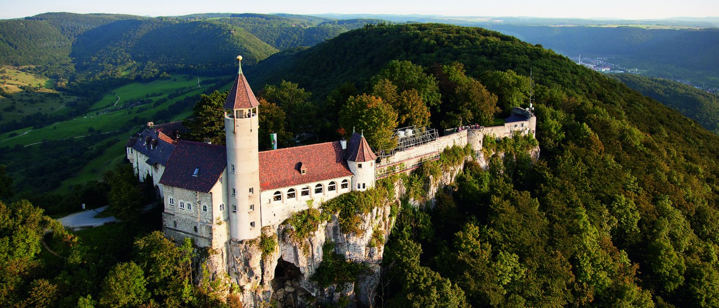 Die Burg Teck thront majestätisch auf einem bewaldeten Hügel, umgeben von grünen Tälern und Wäldern in der Ferne., © © Stuttgart-Marketing GmbH Die Burg Teck thront majestätisch auf einem bewaldeten Hügel, umgeben von grünen Tälern und Wäldern in der Ferne., © © Stuttgart-Marketing GmbH