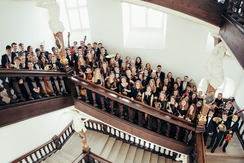 Das Landesjugendorchester Baden-Württemberg posiert auf einer Treppe. Die jungen Musiker halten ihre Instrumente und tragen formelle Kleidung., © Schönblick gemeinnützige GmbH