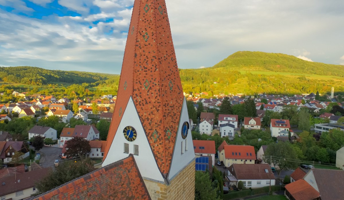 Spitzes Kirchendach der Johanneskirche, im Hintergrund eine Stadt mit roten Dächern und grüner Hügel unter blauem Himmel., © Landkreis Göppingen