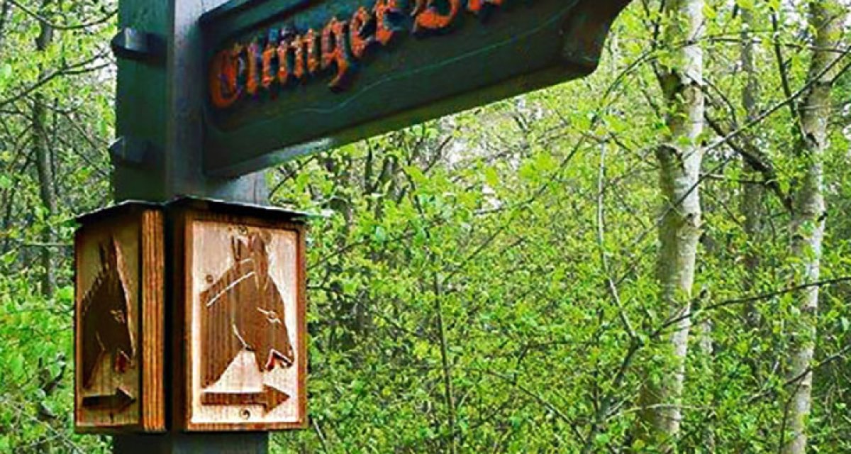 Holzwegweiser im Wald mit der Aufschrift 'Oßinger Blick' und geschnitzten Pferdeköpfen als Dekoration., © Bürgerverein Eltingen e. V. Holzwegweiser im Wald mit der Aufschrift 'Oßinger Blick' und geschnitzten Pferdeköpfen als Dekoration., © Bürgerverein Eltingen e. V.