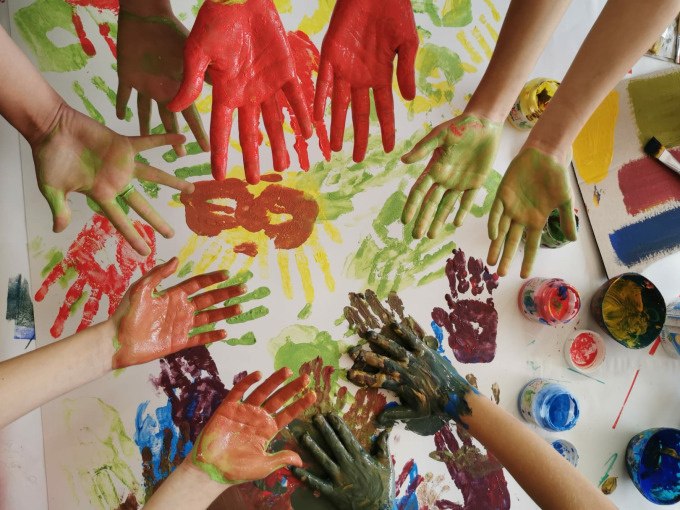 Mehrere bemalte Hände in verschiedenen Farben über einem Blatt mit bunten Handabdrücken. Farbtöpfe und Pinsel liegen daneben., © Kunsthalle Göppingen Mehrere bemalte Hände in verschiedenen Farben über einem Blatt mit bunten Handabdrücken. Farbtöpfe und Pinsel liegen daneben., © Kunsthalle Göppingen