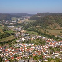 Luftaufnahme von Bad Diutzenbach, umgeben von grünen Hügeln und Wäldern. Im Vordergrund sind Häuser und Straßen zu sehen, im Hintergrund erstreckt sich die Landschaft., © Stuttgart-Marketing GmbH / Achim Mende