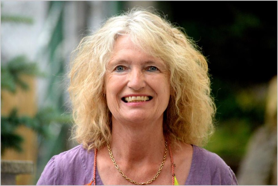 Eine lächelnde Frau mit lockigem, blondem Haar und lila Oberteil steht im Freien., © c_Peter Vogel Eine lächelnde Frau mit lockigem, blondem Haar und lila Oberteil steht im Freien., © c_Peter Vogel