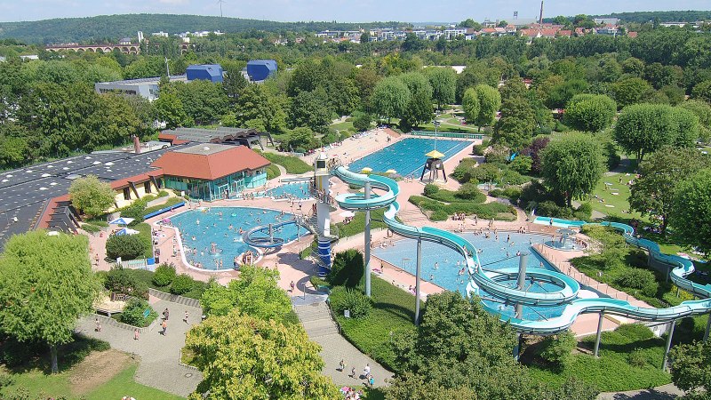 Luftaufnahme des Badeparks Ellental in Bietigheim-Bissingen mit Schwimmbecken, Rutschen und grüner Umgebung., © Badepark Ellental, SWBB
